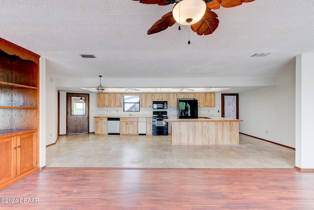 kitchen with black appliances, light wood-type flooring, and a textured ceiling