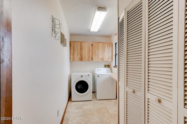 laundry area with a textured ceiling, separate washer and dryer, and cabinets