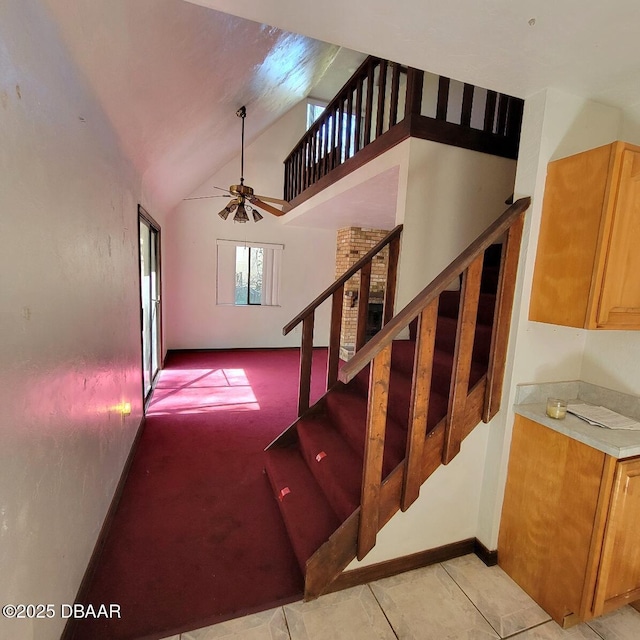 stairway with high vaulted ceiling, baseboards, and a ceiling fan