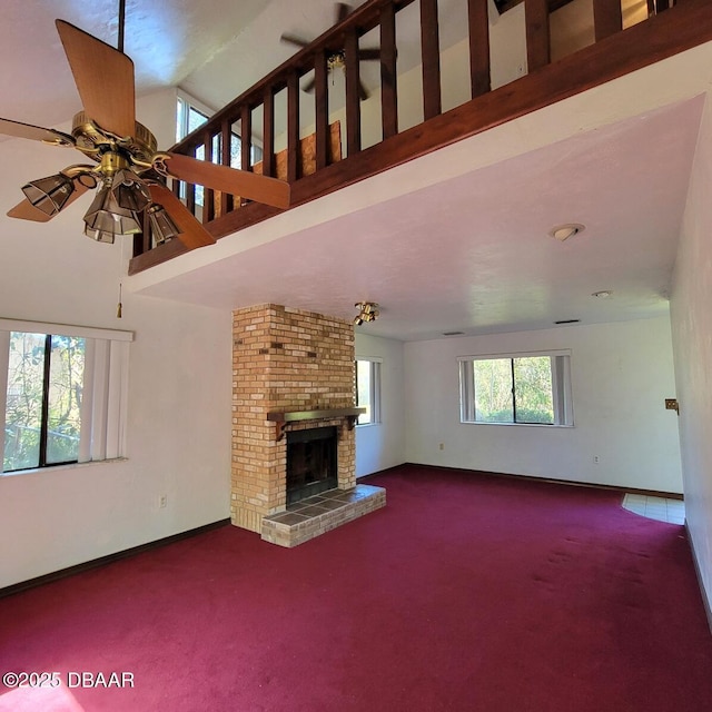 unfurnished living room with a towering ceiling, a fireplace, ceiling fan, and carpet floors