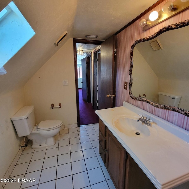 bathroom with vanity, visible vents, vaulted ceiling with skylight, tile patterned floors, and toilet