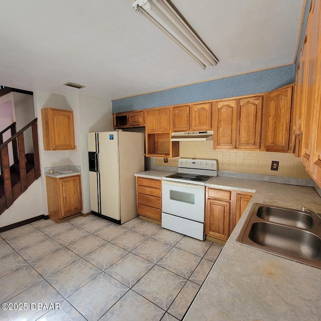 kitchen with a sink, under cabinet range hood, backsplash, white appliances, and light countertops