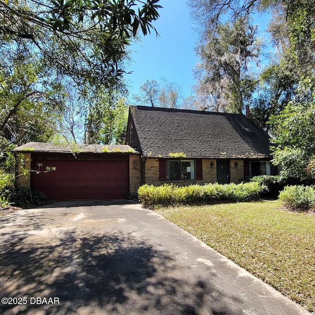 view of front of home with brick siding, a shingled roof, concrete driveway, a front yard, and a garage