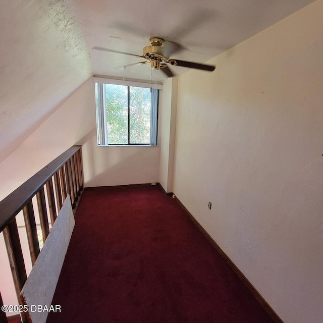 additional living space with lofted ceiling, a ceiling fan, dark colored carpet, and baseboards