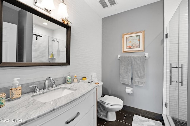 bathroom featuring tile patterned floors, vanity, toilet, and a shower with shower door