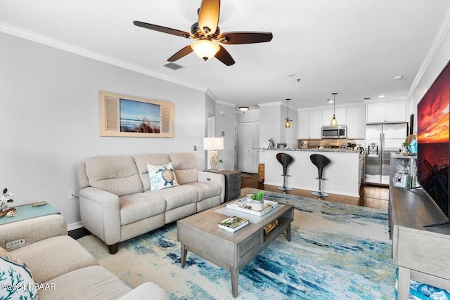 living room with light hardwood / wood-style flooring, ceiling fan, and crown molding