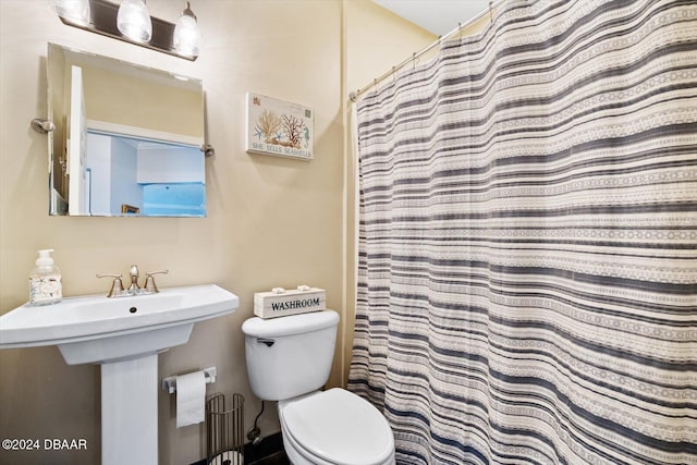 bathroom with sink, a shower with shower curtain, and toilet