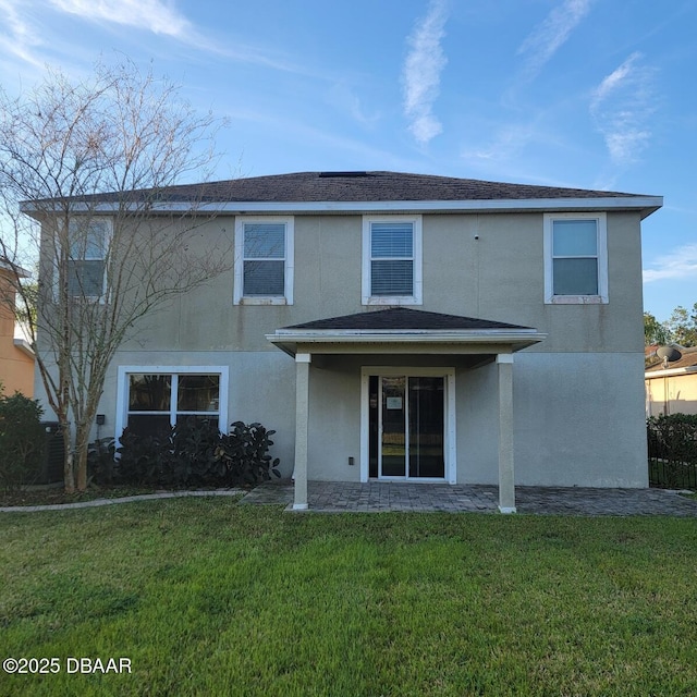 rear view of house with a lawn and stucco siding