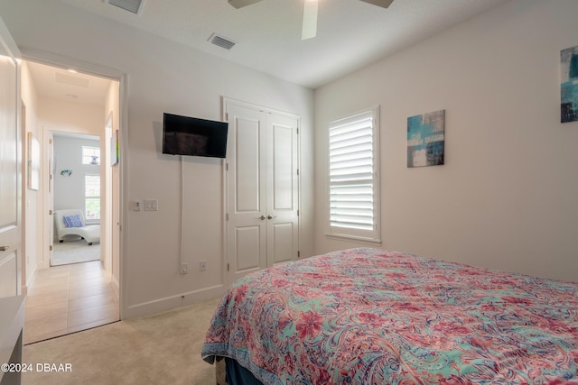 carpeted bedroom with ceiling fan, multiple windows, and a closet