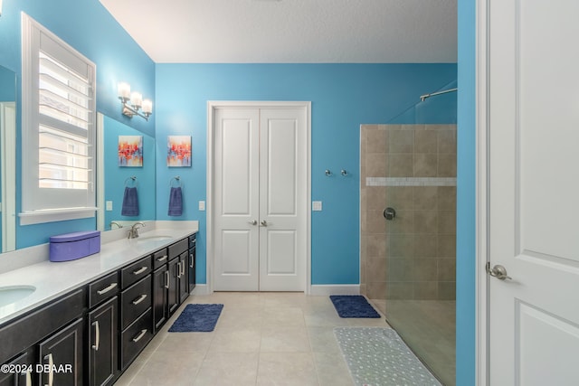 bathroom with vanity, a textured ceiling, tile patterned flooring, and tiled shower