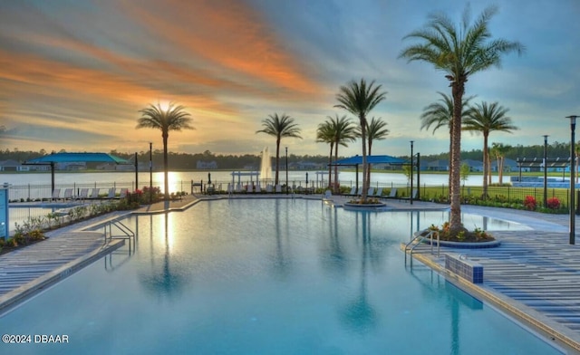 pool at dusk featuring a water view