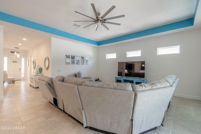 living room featuring ceiling fan, a tray ceiling, and light tile patterned flooring