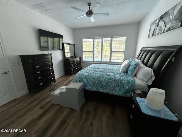 bedroom with ceiling fan, a textured ceiling, and dark hardwood / wood-style flooring