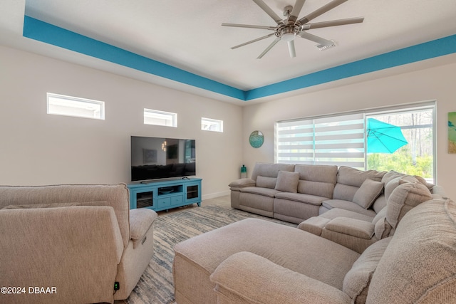 living room with ceiling fan and a tray ceiling