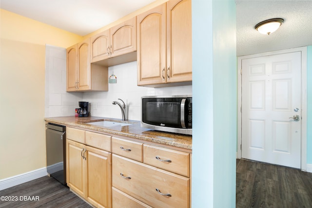 kitchen with appliances with stainless steel finishes, a textured ceiling, light brown cabinetry, sink, and dark wood-type flooring