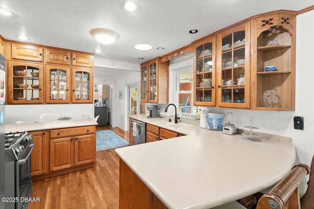 2667 John Anderson Dr, Ormond Beach, FL 32176 - kitchen with appliances with stainless steel finishes, light wood finished floors, a peninsula, light countertops, and brown cabinets
