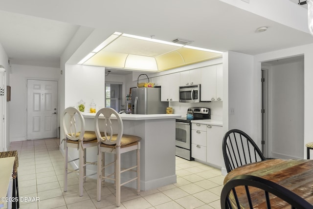 4555 S Atlantic Ave Unit 4209, Ponce Inlet, FL 32127 - kitchen featuring stainless steel appliances, light tile patterned flooring, white cabinets, a kitchen breakfast bar, and light countertops