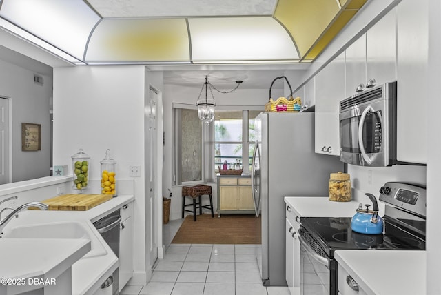 4555 S Atlantic Ave Unit 4209, Ponce Inlet, FL 32127 - kitchen featuring appliances with stainless steel finishes, light countertops, light tile patterned floors, white cabinetry, and a chandelier