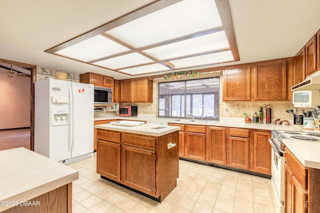 kitchen featuring white appliances, light countertops, a sink, and backsplash