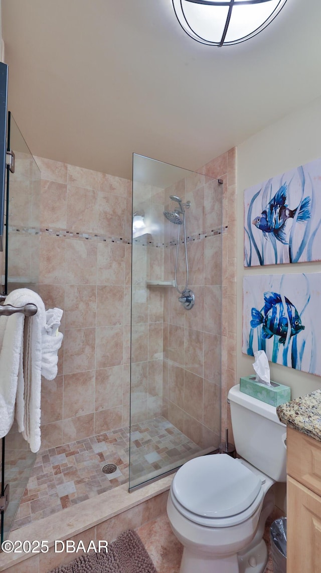 bathroom with toilet, a tile shower, and vanity