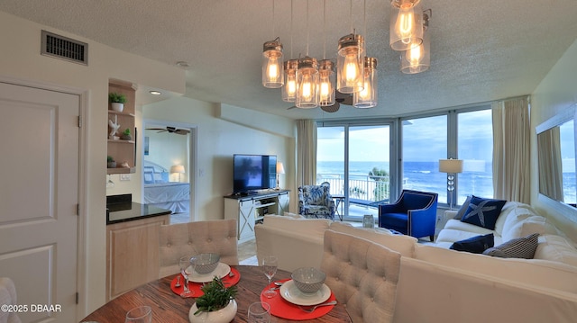 living room featuring ceiling fan with notable chandelier, floor to ceiling windows, and a textured ceiling