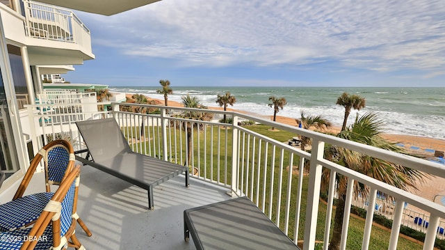 balcony with a water view and a view of the beach