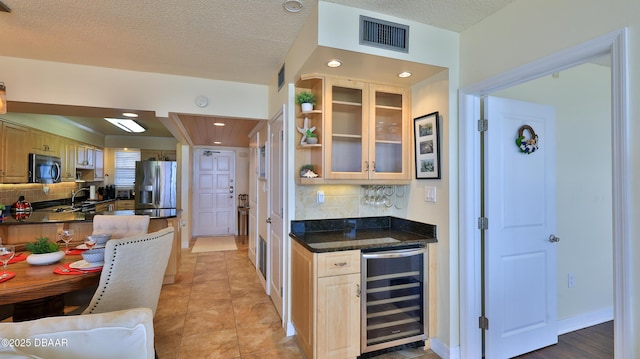 kitchen with wine cooler, backsplash, stainless steel appliances, and a textured ceiling