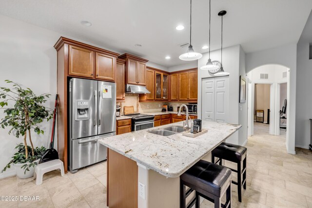 6 Promenade Pl, Palm Coast, FL 32164 - kitchen with appliances with stainless steel finishes, under cabinet range hood, arched walkways, brown cabinetry, and recessed lighting