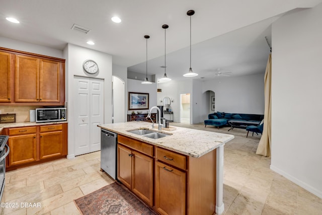 6 Promenade Pl, Palm Coast, FL 32164 - kitchen featuring arched walkways, stainless steel appliances, brown cabinetry, a ceiling fan, and light stone countertops