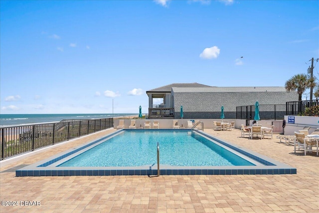 view of pool with a water view and a patio