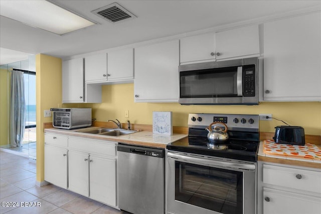 kitchen featuring white cabinetry, sink, light tile patterned flooring, and stainless steel appliances