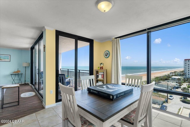 dining space featuring a view of the beach, light hardwood / wood-style floors, a water view, and floor to ceiling windows