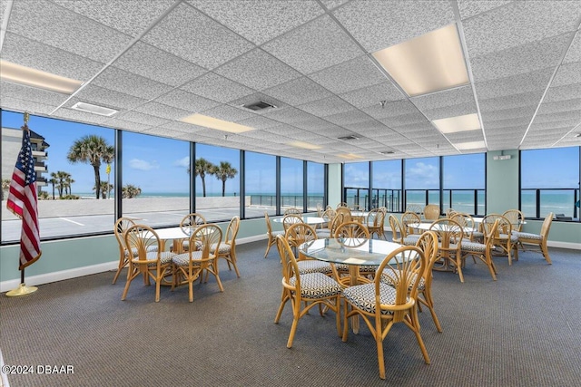 dining room with a water view, floor to ceiling windows, and carpet