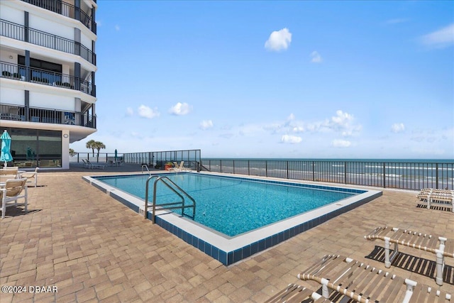 view of pool with a water view and a patio area