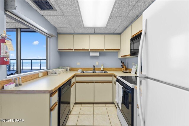 kitchen with black appliances, sink, and cream cabinets