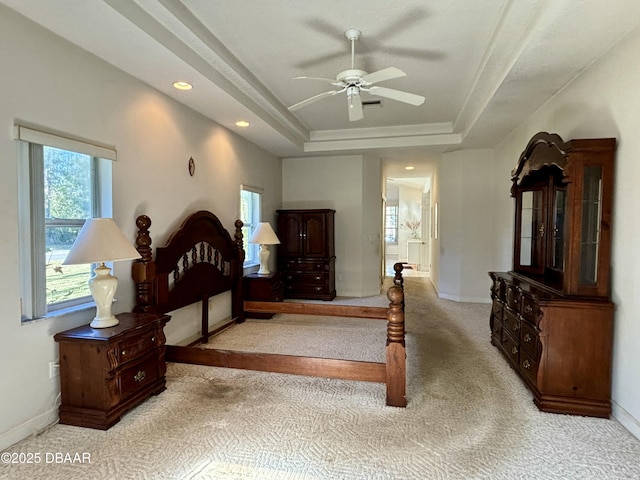 bedroom with a tray ceiling, ceiling fan, and light colored carpet