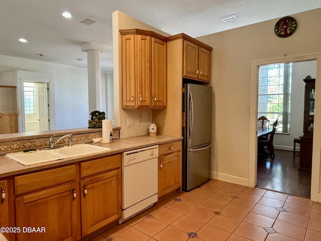 kitchen with a textured ceiling, white dishwasher, sink, light tile patterned floors, and stainless steel refrigerator