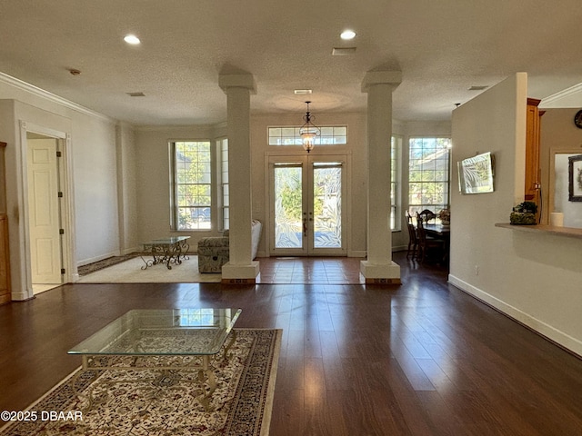 foyer entrance featuring crown molding, ornate columns, dark wood-type flooring, and french doors