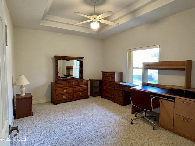 carpeted office with ceiling fan and a tray ceiling