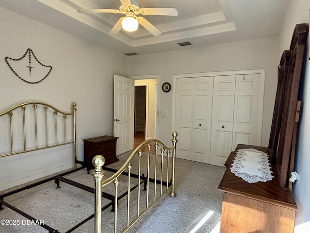 unfurnished bedroom with carpet floors, a closet, a raised ceiling, and ceiling fan