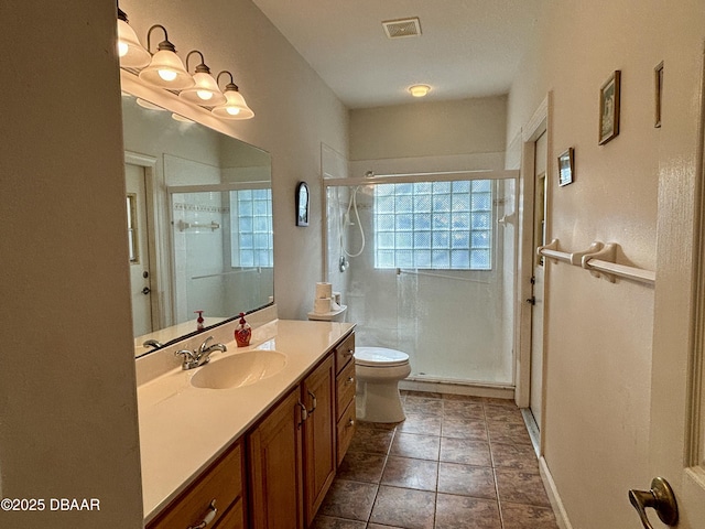 bathroom featuring tile patterned flooring, vanity, a shower with shower door, and toilet