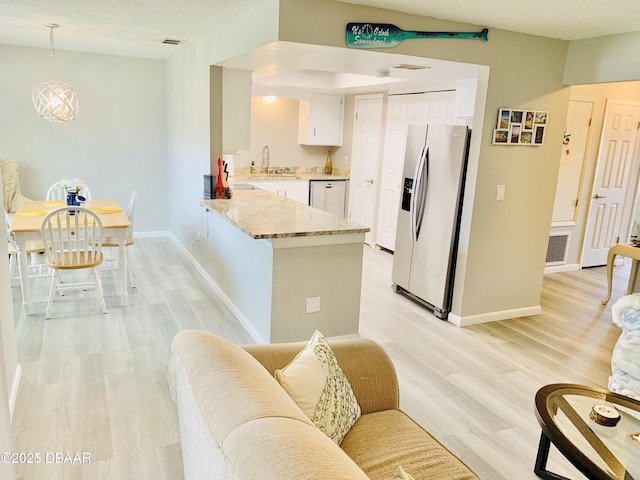 415 Banana Cay Dr Unit J, South Daytona, FL 32119 - kitchen featuring stainless steel refrigerator with ice dispenser, a peninsula, white cabinets, light wood-style floors, and light stone countertops