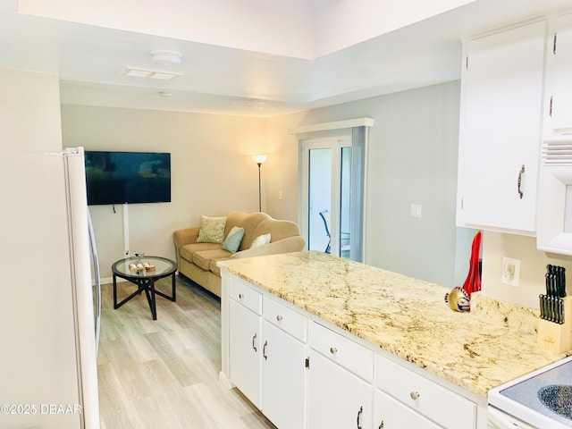 415 Banana Cay Dr Unit J, South Daytona, FL 32119 - kitchen featuring freestanding refrigerator, light wood finished floors, white cabinetry, and light stone countertops