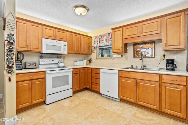 kitchen with a textured ceiling, white appliances, tasteful backsplash, and sink