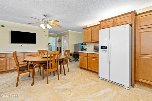 kitchen with a textured ceiling, white fridge with ice dispenser, and ceiling fan