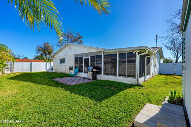 rear view of property with a lawn, a sunroom, and a patio