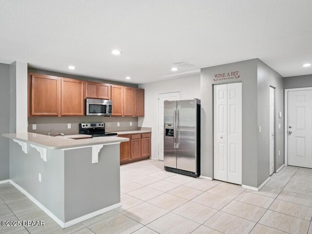 567 Mount Olympus Blvd, New Smyrna Beach, FL 32168 - kitchen featuring appliances with stainless steel finishes, a peninsula, light countertops, a breakfast bar area, and recessed lighting
