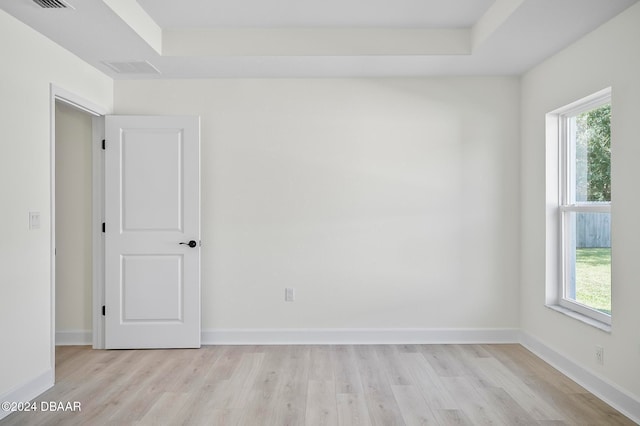 spare room with light hardwood / wood-style floors and a raised ceiling