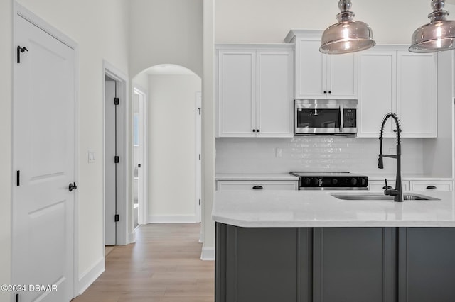 kitchen featuring light wood-type flooring, white cabinetry, pendant lighting, and stainless steel appliances