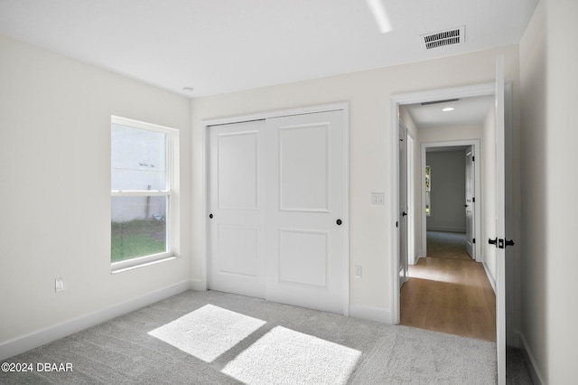 unfurnished bedroom featuring light carpet and a closet